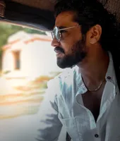 Vignesh in sunglasses and a white shirt, looking out from an auto-rickshaw